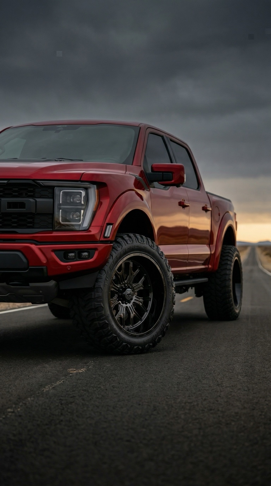 Red Ford F-150 Raptor on a dark open road